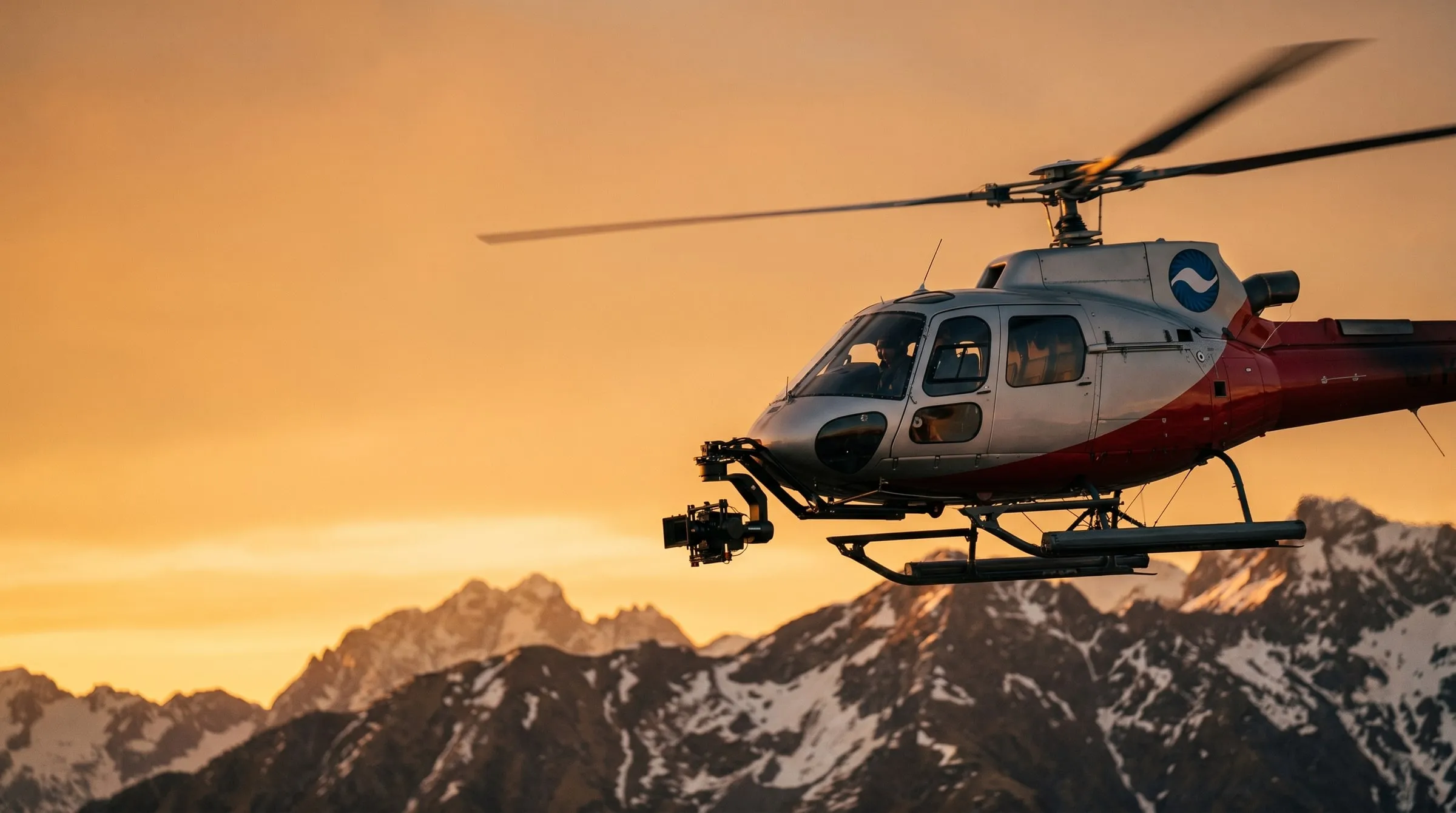 A Coldstream AStar camera-ship helicopter with a nose-mounted cinema gimbal flying at sunset