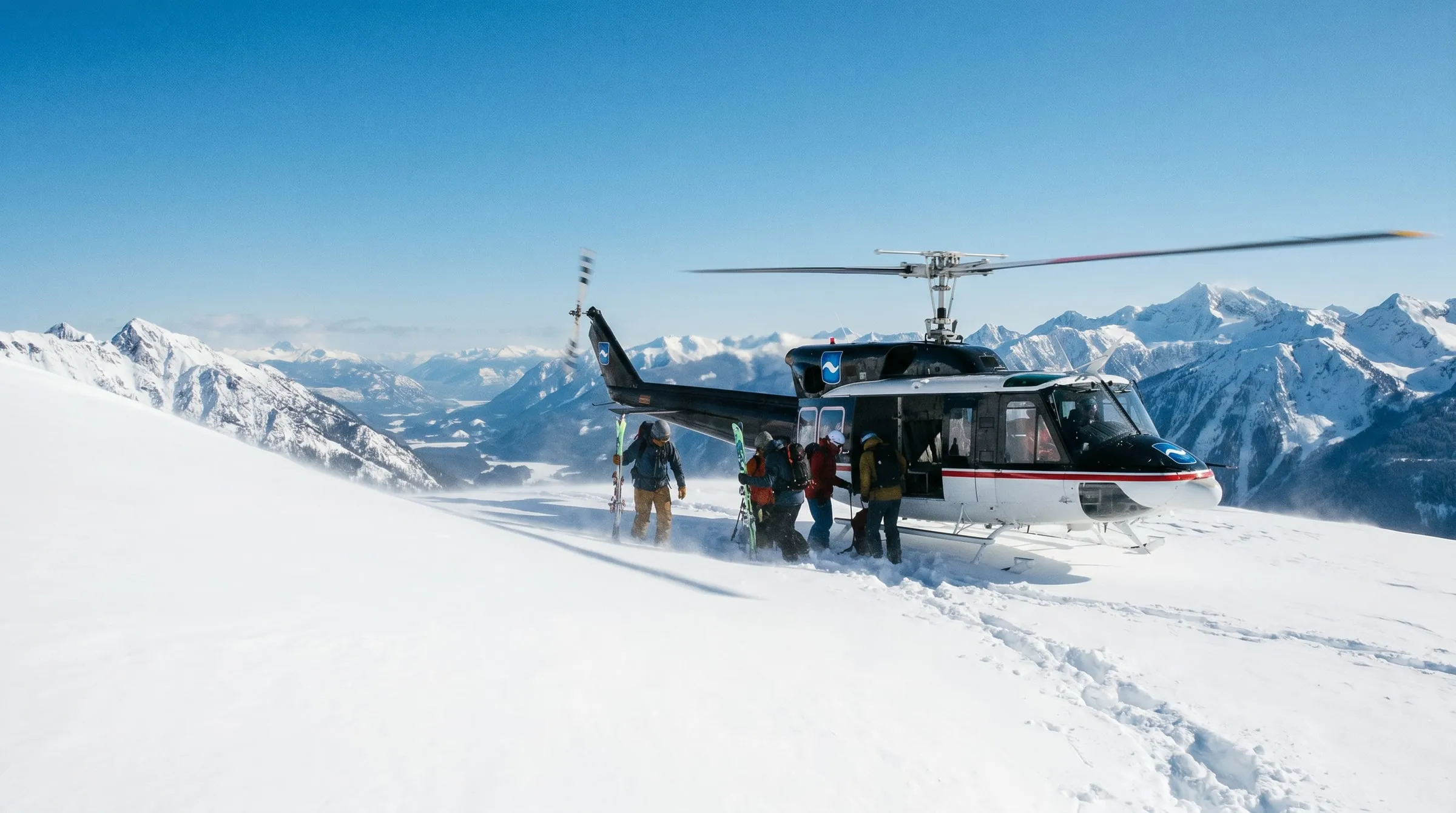 A Coldstream Bell 212 helicopter landed on a snowy ridge as backcountry skiers unload